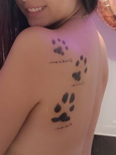 a woman with tattoos on her back and paw prints painted on the side of her body