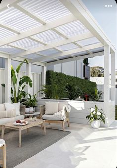 an outdoor living area with white furniture and plants