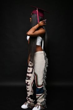 a woman with long hair and a graduation cap on her head is standing in front of a black background