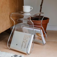 a stack of magazines sitting on top of a table next to a potted plant