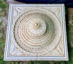 an intricately designed tile on the ground with grass and rocks in the foreground