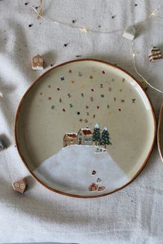 a plate with an image of a house and trees on it, surrounded by confetti sprinkles