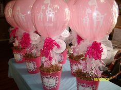 pink giraffe balloons are in flower pots on a table