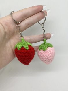 two crocheted strawberries are being held by a hand