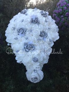 a bouquet of white and blue flowers in the shape of a heart on top of some bushes