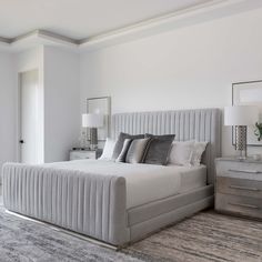 a large bed sitting in the middle of a bedroom next to a dresser and lamp