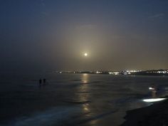 some people are walking on the beach at night