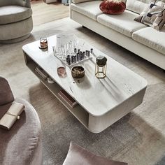 a living room filled with furniture and a white coffee table surrounded by pillows on top of carpeted flooring