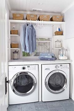 a washer and dryer in a white laundry room with open shelving on the wall