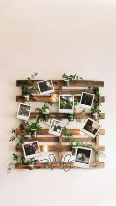 a wooden pallet filled with photos and greenery hanging on the side of a wall