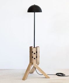 a table lamp made out of wood with a black shade on it and a cord connected to the base