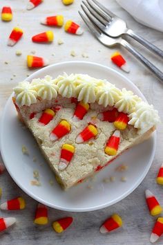 a white plate topped with a slice of cake covered in candy corn and marshmallows