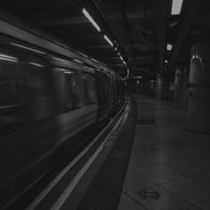 black and white photo of subway train passing by in the dark with light from windows