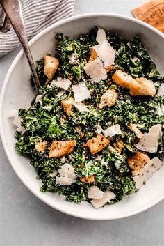 a white bowl filled with greens and croutons