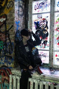 a man standing in front of a window covered in graffiti