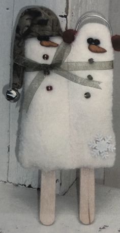 two snowmen made out of popsticks with a hat and scarf on them