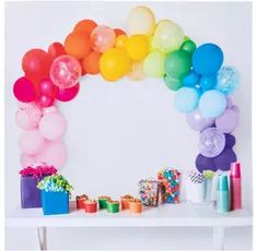 a table topped with balloons and confetti next to a white wall in the background