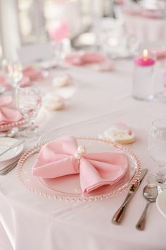 the table is set with pink napkins and silverware