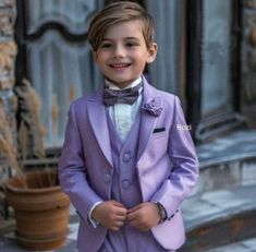 a young boy dressed in a purple suit and bow tie smiling at the camera with his hands in his pockets