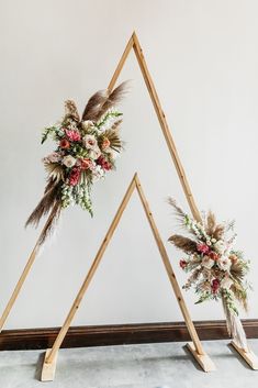 two wooden triangles decorated with flowers and feathers