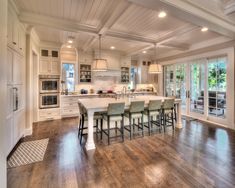 a large kitchen with white cabinets and wooden floors