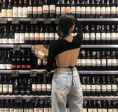 a woman standing in front of a display of wine bottles