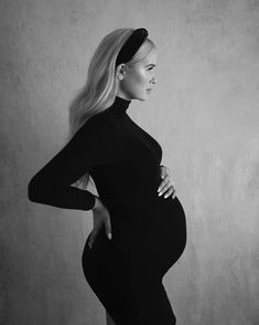 a pregnant woman poses for a black and white photo with her hands on her hips