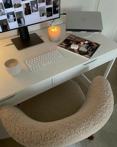 a white desk with a computer, keyboard and mouse on it next to a lit candle