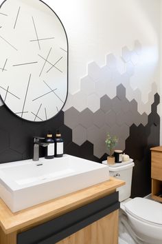 a bathroom with black and white hexagonal tiles on the wall, wooden countertop