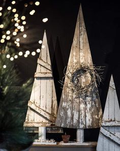 three wooden christmas trees with lights in the background