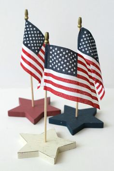 three small wooden stars with american flags on them next to each other, one is red white and blue