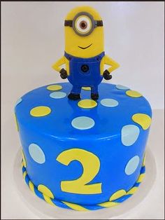 a blue and yellow birthday cake with a minion on top