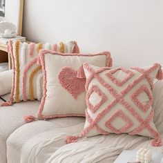 some pillows are sitting on a couch in front of a white wall and a mirror