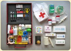 the contents of an emergency medical kit are neatly organized in a red case on a gray surface