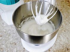 a whisk in a metal bowl next to a blender