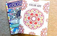 two coloring books sitting on the floor next to each other, one with an intricate design