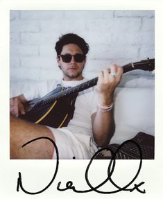 a man sitting on a couch holding a guitar in his hand and wearing sunglasses with the word o'call written across it