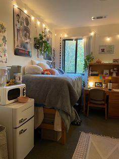 a bed room with a neatly made bed next to a window and a small refrigerator