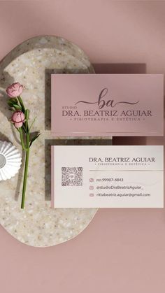 two business cards sitting on top of a white plate next to a flower and fan