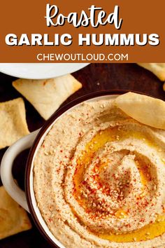 roasted garlic hummus in a bowl with pita chips around it and text overlay that reads roasted garlic hummus