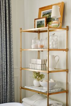 a gold shelf filled with white dishes and vases on top of it's sides