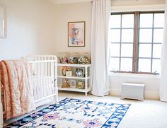 a baby's room with a crib, rug and window