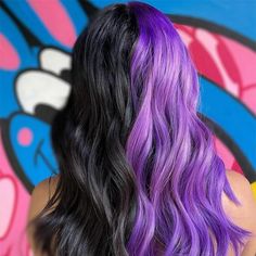 the back of a woman's head with purple and black hair in front of a graffiti wall