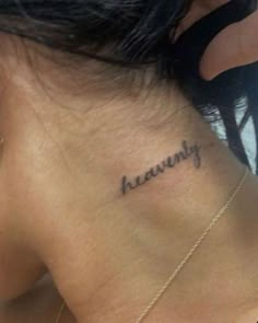 the back of a woman's neck with her name tattooed in cursive writing