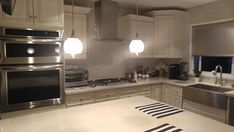 a modern kitchen with stainless steel appliances and white counter tops, along with black and white stripes on the floor