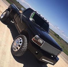 a black truck parked on top of a dirt road