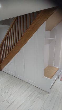 an empty room with white cabinets under the stair case and wooden handrails on the wall