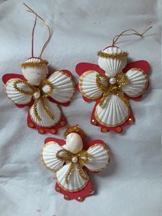 three seashell ornaments are hanging from red and white paper with gold sequins