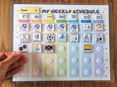 a person holding up a sticker calendar on top of a wooden table with lots of magnets