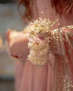 a woman in a pink dress holding a bouquet of white and pink flowers on her arm